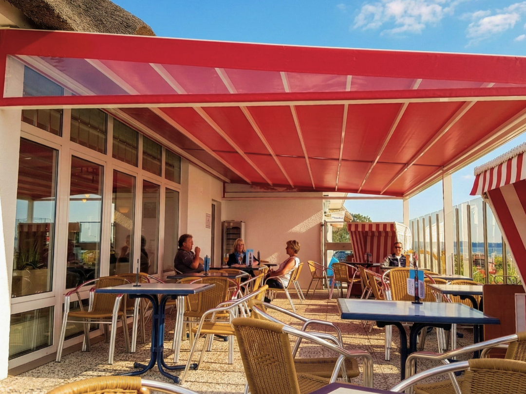 Rotes textiles Gastro-Dach überspannt eine Außengastronomie an der Küste