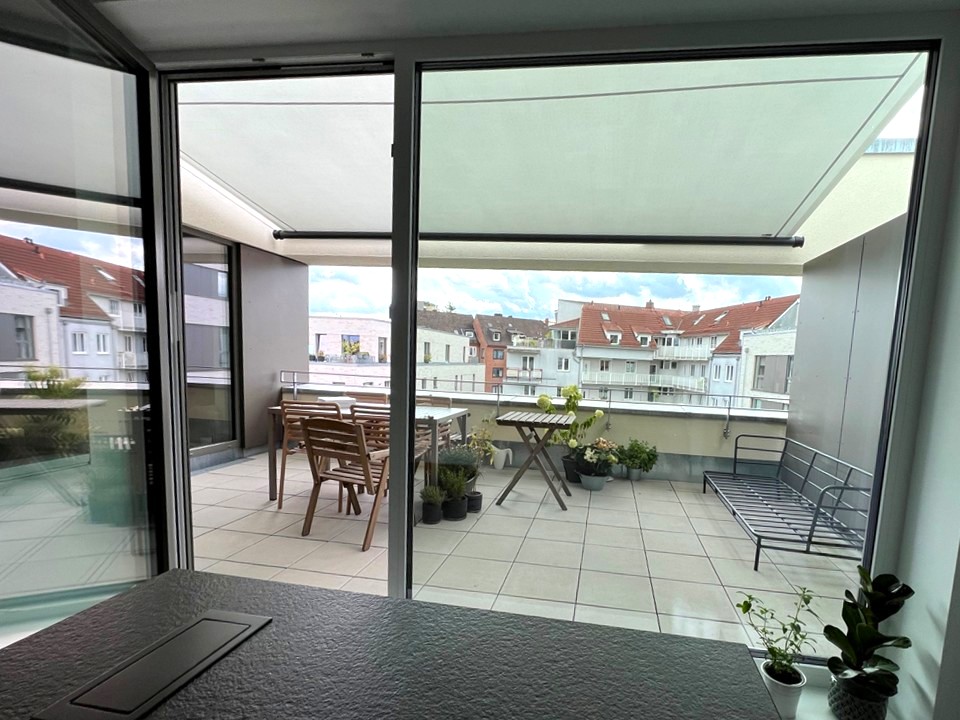 Blick von Innenraum nach draußen auf den Dachbalkon, das helle Segel verdunkelt den Innenraum nicht