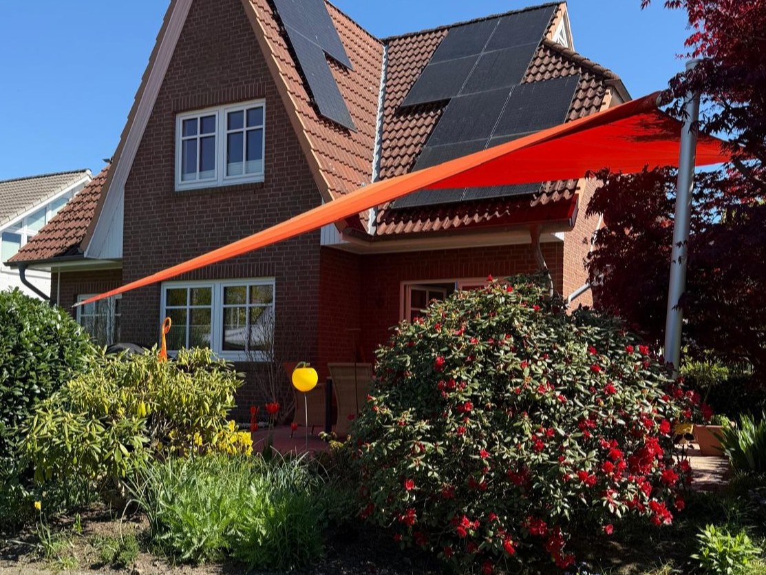 rotes sonnensegel mit höhenverstellung vor einem Einfamilienhaus in hamburg schnelsen von zschimmer