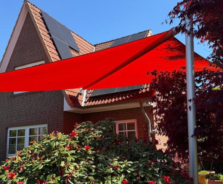rotes sonnensegel in blühendem Garten vor einem Einfamilienhaus mit backsteinfassade in hmaburg-schnelsen von zschimmer