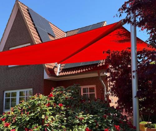 rotes sonnensegel in blühendem Garten vor einem Einfamilienhaus mit backsteinfassade in hmaburg-schnelsen von zschimmer