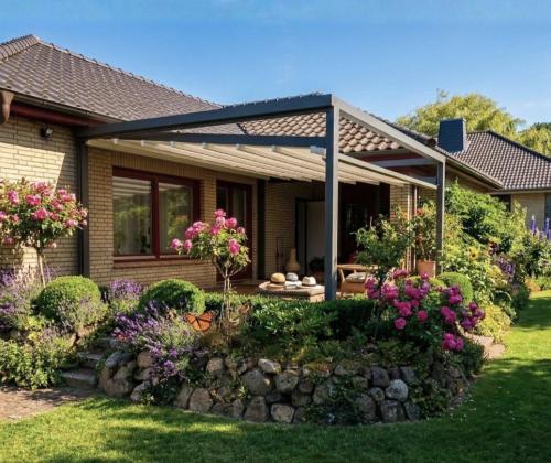 Ausgefahrene, weiße Pergola Markise Sunrain Q mit abgesenkten Markisentuch überspannt die Terrasse eines Einfamilienhaus