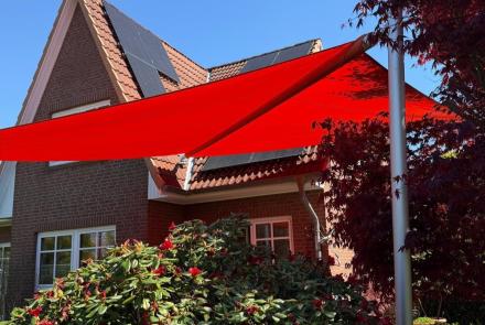 rotes sonnensegel in blühendem Garten vor einem Einfamilienhaus mit backsteinfassade in hmaburg-schnelsen von zschimmer
