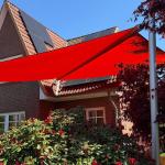 rotes sonnensegel in blühendem Garten vor einem Einfamilienhaus mit backsteinfassade in hmaburg-schnelsen von zschimmer