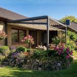 Ausgefahrene, weiße Pergola Markise Sunrain Q mit abgesenkten Markisentuch überspannt die Terrasse eines Einfamilienhaus